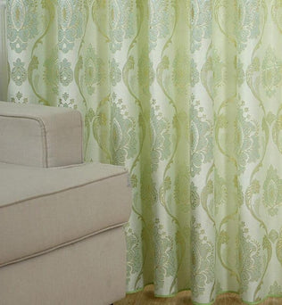 Rideau décoratif vert clair à motifs baroques avec canapé beige, idéal pour salon, apportant élégance et style à votre intérieur moderne.