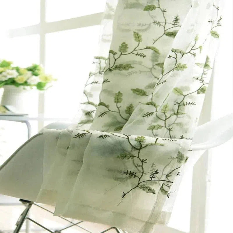Rideau translucide avec motif végétal de feuilles vertes, créant une ambiance naturelle et lumineuse dans la pièce, idéal pour ajouter une touche d'élégance à la décoration intérieure.