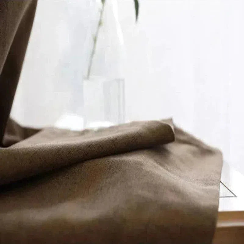 Texte alternatif SEO : "Rideau en lin marron clair sur une table en bois, idéal pour une décoration intérieure moderne et chaleureuse. Matière de qualité pour une ambiance élégante et accueillante dans votre salon ou chambre."