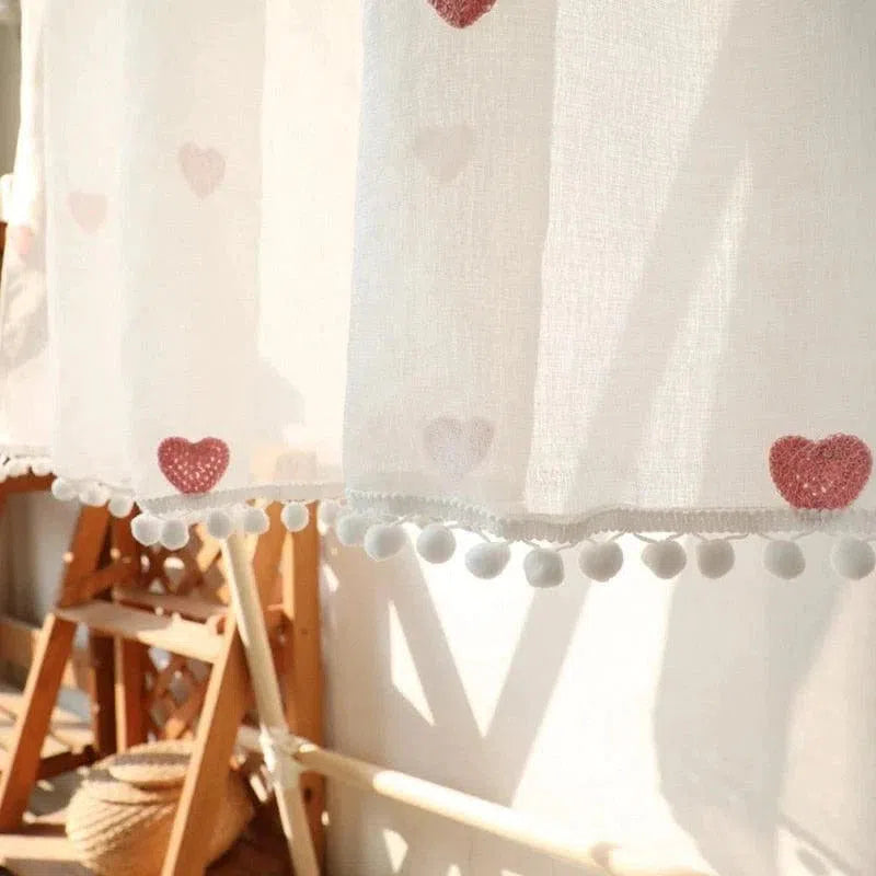 Rideau décoratif blanc avec motifs de cœurs rouges et bordure de pompons, idéal pour ajouter une touche chaleureuse et romantique à votre intérieur. Parfait pour la chambre ou le salon, il laisse passer la lumière tout en embellissant votre espace.