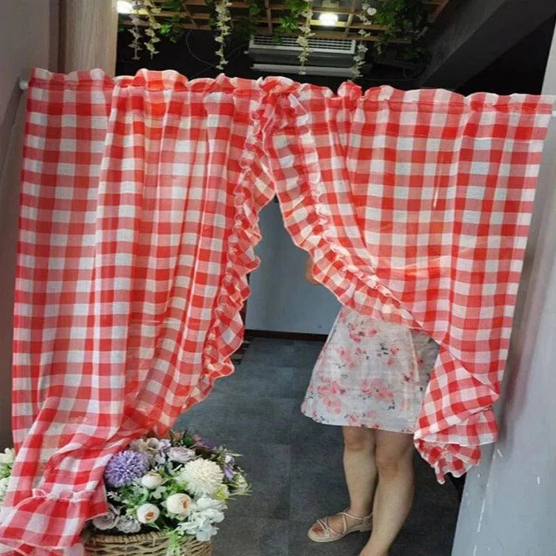 Rideau à carreaux rouges et blancs avec volants décoratifs, parfait pour ajouter une touche rustique et charmante à votre intérieur. Idéal pour séparer les espaces ou embellir vos fenêtres. Panier fleuri en décoration au pied du rideau, apportant une ambiance champêtre et accueillante à votre espace de vie.