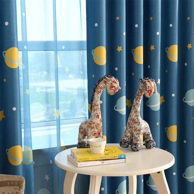 Rideau enfant motif espace bleu avec planètes jaunes, parfait pour créer une ambiance cosmique dans la chambre. Décoration originale avec girafes en peluche sur une table ronde blanche, ajoutant une touche ludique et chaleureuse. Idéal pour stimuler l'imagination des enfants tout en embellissant leur espace de vie.