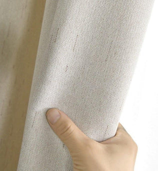 Rideau beige élégant pour salon moderne, détails de texture, tenue à la main, accessoire décoration intérieure.