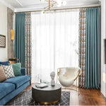 Rideau élégant avec motifs floraux et couleurs sobres, idéal pour rehausser la décoration intérieure d'un salon moderne. Le design contemporain s'intègre parfaitement avec un canapé bleu et des accessoires déco chic, créant une ambiance raffinée et accueillante. Parfait pour donner une touche sophistiquée à toute pièce.