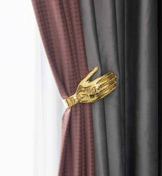 Attache-rideau originale en forme de main dorée tenant des rideaux élégants, ajoutant une touche artistique et moderne à votre décoration intérieure. Accessoire pratique et décoratif pour sublimer vos fenêtres. Idéal pour un salon, une chambre ou un bureau.
