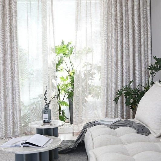Salon moderne avec rideaux élégants et plantes vertes, mettant en valeur une ambiance lumineuse et naturelle. Les tables basses rondes apportent une touche contemporaine, offrant un espace accueillant pour la détente et la lecture.