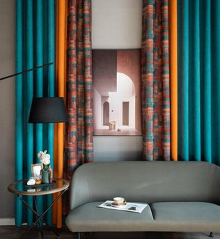 Rideaux colorés et modernes pour salon, décorés de motifs géométriques vibrants. Idéal pour ajouter une touche contemporaine et élégante à votre intérieur. Combine des teintes vives comme le turquoise et l'orange pour un design harmonieux. Accompagne un canapé gris et une table d'appoint, créant une atmosphère accueillante et stylée.
