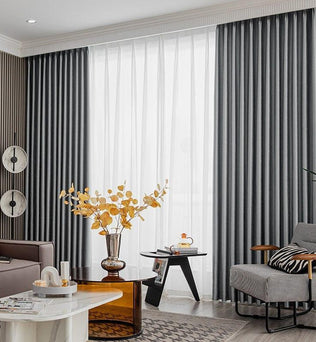 Rideaux occultants gris élégants dans un salon moderne. L'espace est décoré avec des meubles contemporains, comprenant un canapé confortable, une table basse chic, un fauteuil design et une décoration murale artistique. Luminosité douce grâce aux rideaux et à la lumière naturelle, créant une ambiance chaleureuse et accueillante. Parfait pour ajouter une touche de style et d'élégance à votre intérieur.