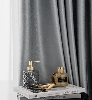 Rideaux élégants de couleur grise, parfaits pour créer une ambiance sophistiquée dans votre salon. Accessoires de décoration modernes avec flacons de parfum et livres empilés, ajoutant une touche de raffinement à votre espace intérieur. Découvrez comment ces éléments peuvent transformer votre maison en un havre de paix chic et accueillant.