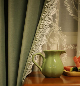 Rideau élégant vert avec bordure en dentelle perlée, idéal pour une décoration intérieure raffinée. Place sur un meuble en bois, accompagnée d'une carafe verte et de morceaux de pastèque fraîche. Ambiance chaleureuse et accueillante pour un salon ou une salle à manger. Parfait pour ajouter une touche de sophistication et de charme à votre espace.