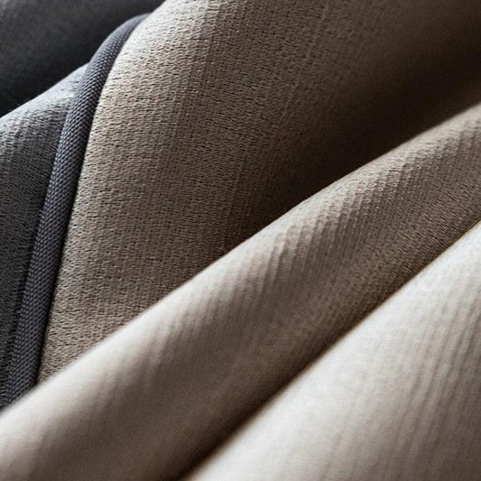 Gros plan sur un tissu épais aux nuances de gris et brun, idéal pour la décoration intérieure. L'élégance des plis et la texture ajoutent une touche sophistiquée à tout espace. Parfait pour créer une ambiance chaleureuse et moderne dans votre maison.