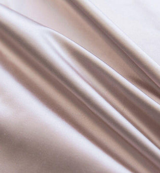 Texture fluide et soyeuse d'un tissu luxueux rose pâle, idéal pour la confection de vêtements élégants et raffinés, offrant un drapé élégant et une brillance subtile qui rehaussera toute création.