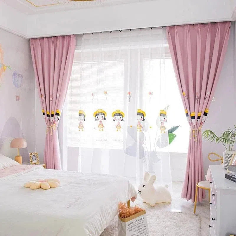 Chambre d'enfant décorée avec rideaux roses élégants, ornés de motifs ludiques, apportant une touche de couleurs vives et gaies. La chambre dispose d'un lit douillet et d'éléments de décoration mignons, créant un espace accueillant et chaleureux idéal pour les enfants. Ambiance lumineuse idéale pour un espace plein de vie et de confort.