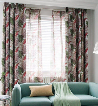 Rideaux à motif tropical coloré devant une fenêtre avec stores vénitiens. Décoration intérieure mettant en avant un canapé bleu clair et un coussin assorti dans un salon moderne et lumineux. Atmosphère apaisante et élégante, soulignée par une lampe au design minimaliste. Idéal pour ajouter une touche de nature et de style à votre espace de vie.