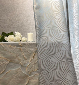Rideaux élégants avec motifs géométriques modernes pour décoration intérieure. Ambiance chic et raffinée avec fond de table assorti. Idéal pour salon ou chambre, apportant une touche de luxe à votre espace. Accessoires de décoration comme fleurs blanches et chandelle pour une atmosphère chaleureuse et accueillante.