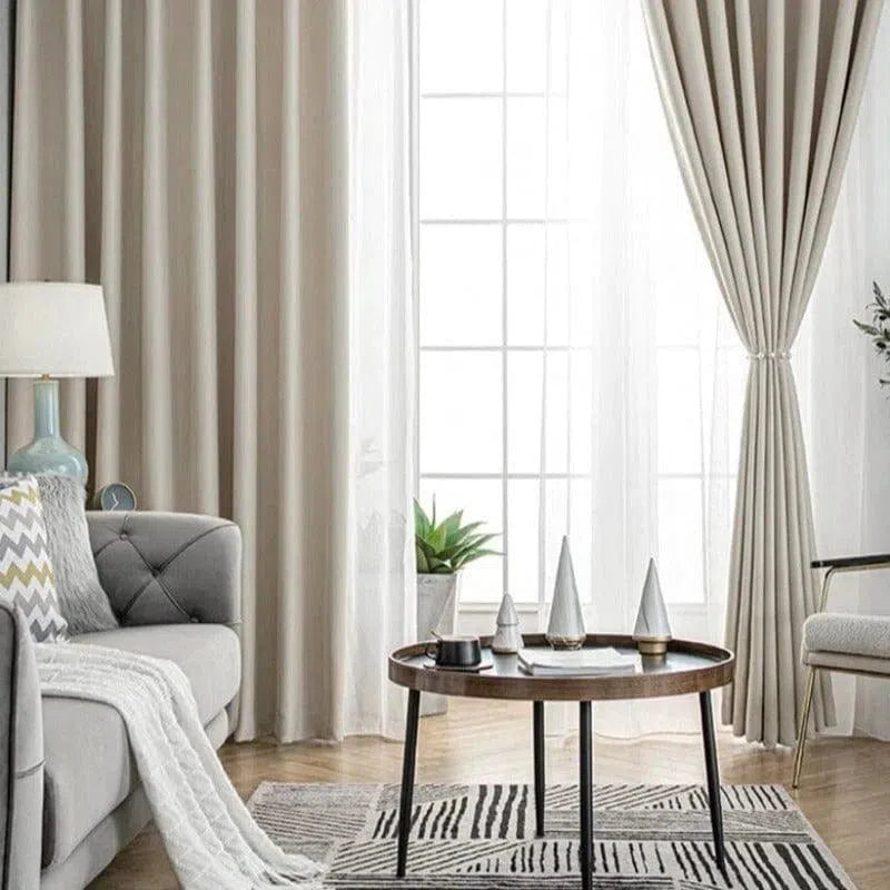 Rideaux élégants pour salon moderne, encadrant une large fenêtre avec lumière naturelle. Ambiance épurée avec canapé confortable, table basse design et décoration minimaliste. Idéal pour un intérieur chic et contemporain. Décoration d'intérieur harmonieuse avec couleurs neutres et motifs géométriques.
