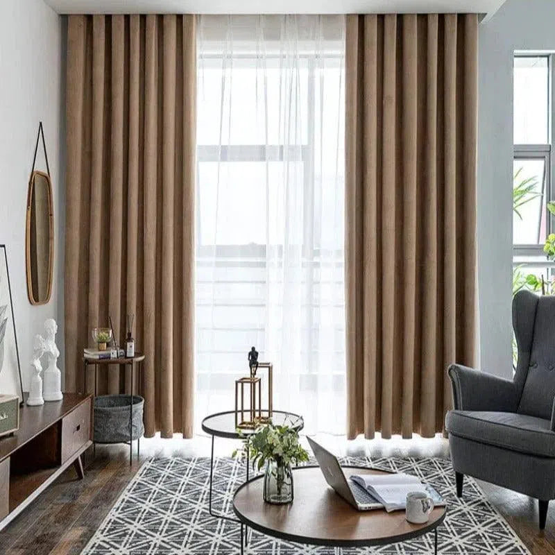 Rideaux élégants de couleur beige dans un salon moderne au design épuré. Mise en valeur de la luminosité grâce à une fenêtre avec voilage blanc. Décoration intérieure avec des tables basses circulaires, un tapis géométrique, un fauteuil confortable et des éléments décoratifs tels que des plantes et des sculptures. Style contemporain et ambiance chaleureuse pour un espace de vie accueillant.