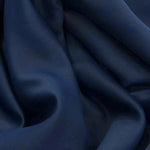 Gros plan sur un tissu bleu marine élégant avec des plis doux, idéal pour un drapé élégant dans la confection vestimentaire ou la décoration d'intérieur. Ce tissu est parfait pour créer une atmosphère sophistiquée et moderne.