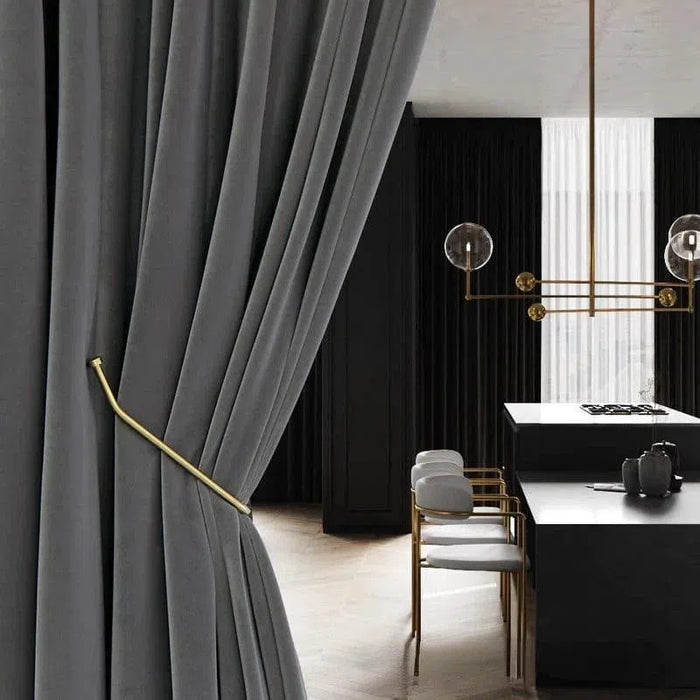 Rideau élégant gris foncé dans un intérieur moderne, avec un embrasse en métal doré, ajoutant une touche de sophistication au salon, combiné avec un mobilier chic et contemporain sous un éclairage design.
