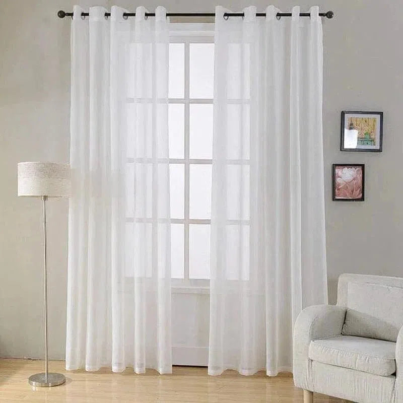 Rideaux blancs élégants pour salon moderne, ajoutant luminosité et élégance à votre intérieur. Ils sont suspendus à une tringle noire devant une grande fenêtre. Décoration épurée avec un canapé confortable, une lampe sur pied et des tableaux muraux. Idéal pour créer une ambiance chaleureuse et accueillante.