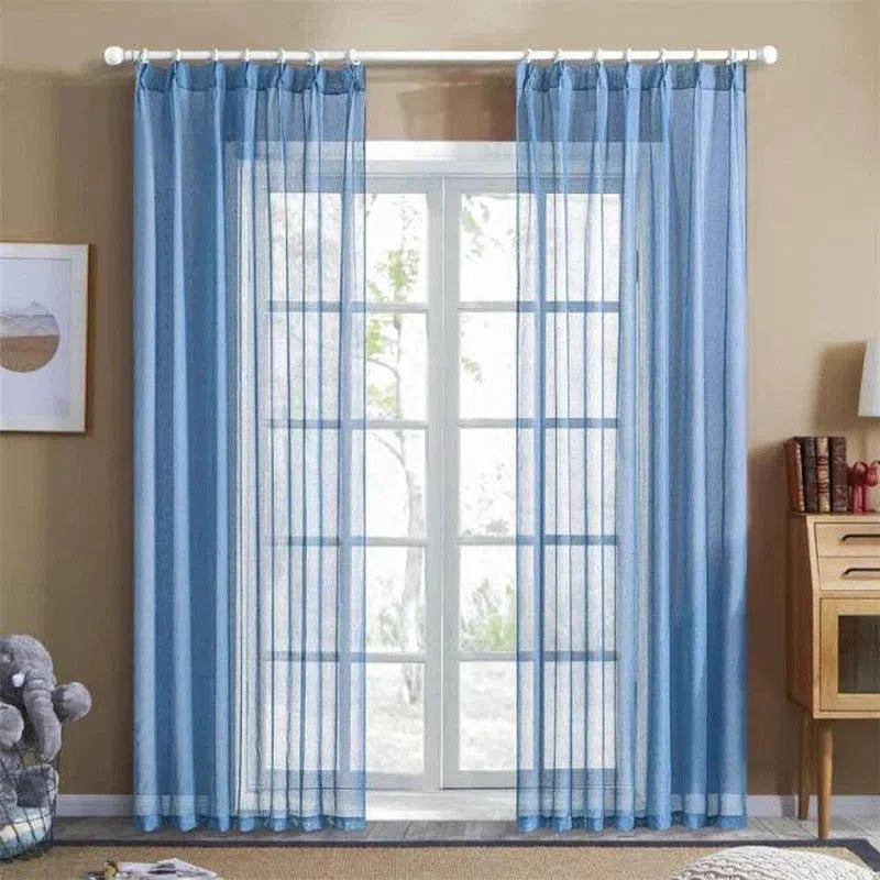 Rideaux bleus transparents suspendus devant une grande fenêtre dans un salon moderne, apportant une ambiance lumineuse et élégante à la pièce. Idéal pour la décoration intérieure, les rideaux laissent passer la lumière tout en ajoutant une touche de couleur apaisante. Parfait pour embellir un salon ou une chambre tout en conservant l'intimité.