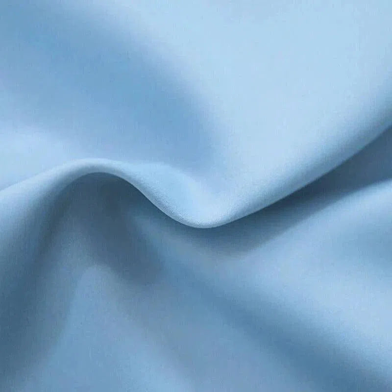 Image d'un tissu bleu clair avec des plis élégants, idéal pour la décoration d'intérieur et la création de vêtements sur mesure. Ce tissu ajoute une touche de douceur et de raffinement à vos projets créatifs.