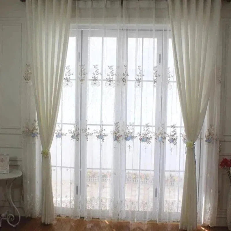 Rideaux élégants blancs sur une grande fenêtre avec un motif floral, ajoutant une touche de sophistication et de luminosité à l'intérieur d'une pièce moderne. Parfaits pour filtrer la lumière tout en décorant le salon ou la chambre à coucher. Idéal pour créer une atmosphère accueillante et stylée.