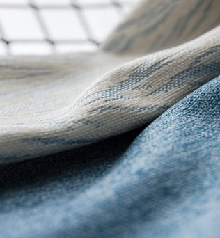 Gros plan sur texture délicate de tissu avec nuances de bleu et beige. Évoque l'élégance et le confort, idéal pour la mode ou la décoration intérieure moderne, apportant une touche subtile et raffinée à votre espace. Parfait pour les amateurs de design élégant et raffiné.