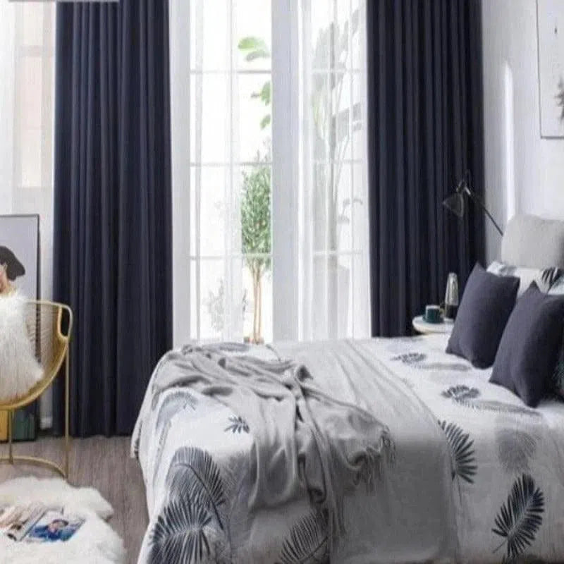 Texte alternatif : "Chambre élégante avec rideaux opaques bleu marine, idées de décoration intérieure moderne, ambiance cosy et lumineuse, literie aux motifs nature."