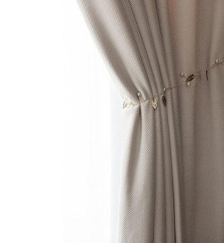 Rideau élégant beige avec un motif texturé, agrémenté d'une chaînette décorative de perles et de petites feuilles dorées, idéal pour apporter une touche de sophistication à votre intérieur. Parfait pour le salon ou la chambre, ce rideau combine design moderne et charme intemporel.