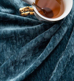 Tasse de thé élégante posée sur un tissu bleu raffiné, créant une ambiance chaleureuse et sophistiquée idéale pour la décoration intérieure. Parfait pour ajouter une touche de luxe à votre espace de vie.