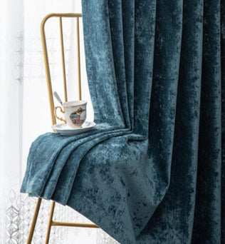 Rideau bleu élégant drapé sur une chaise dorée, avec une tasse de thé raffinée posée dessus. Idéal pour ajouter une touche de luxe et de sophistication à votre intérieur tout en apportant une ambiance chaleureuse et accueillante à votre salon ou chambre.