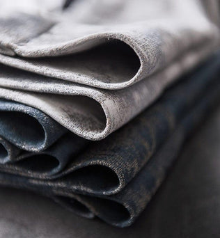 Ensemble de tissus pliés aux nuances de gris et bleu, parfait pour la confection de vêtements élégants ou d'ameublement moderne, offrant un design raffiné et contemporain pour vos projets créatifs.