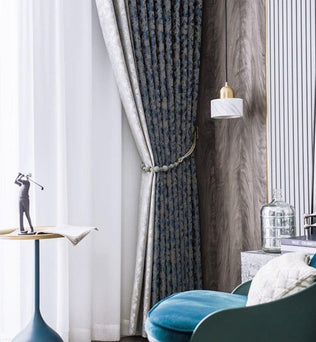 Rideaux élégants dans un salon moderne, créant une ambiance chic et raffinée. Ce décor met en valeur un fauteuil confortable avec une teinte bleue apaisante, une table d'appoint moderne avec une sculpture artistique, et un éclairage pendulaire qui apporte une touche sophistiquée à l'ensemble du design intérieur. Parfait pour améliorer l'esthétique de votre espace de vie.