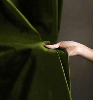 Image d'une main ajustant un rideau vert, capturant l'essence d'une décoration intérieure élégante et moderne, idéale pour sublimer votre espace de vie tout en ajoutant une touche de sophistication et de couleur.