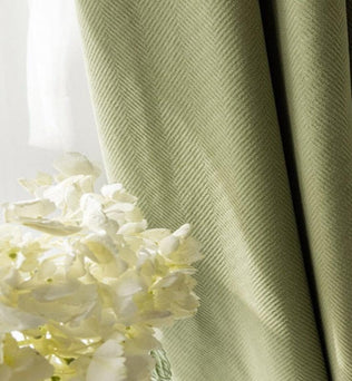 Rideau vert élégant avec motifs en chevrons, idéal pour ajouter une touche de sophistication à votre décoration intérieure. Parfait pour salon ou chambre, ce rideau offre une ambiance apaisante et se marie harmonieusement avec un bouquet de fleurs blanches pour un intérieur lumineux et accueillant.