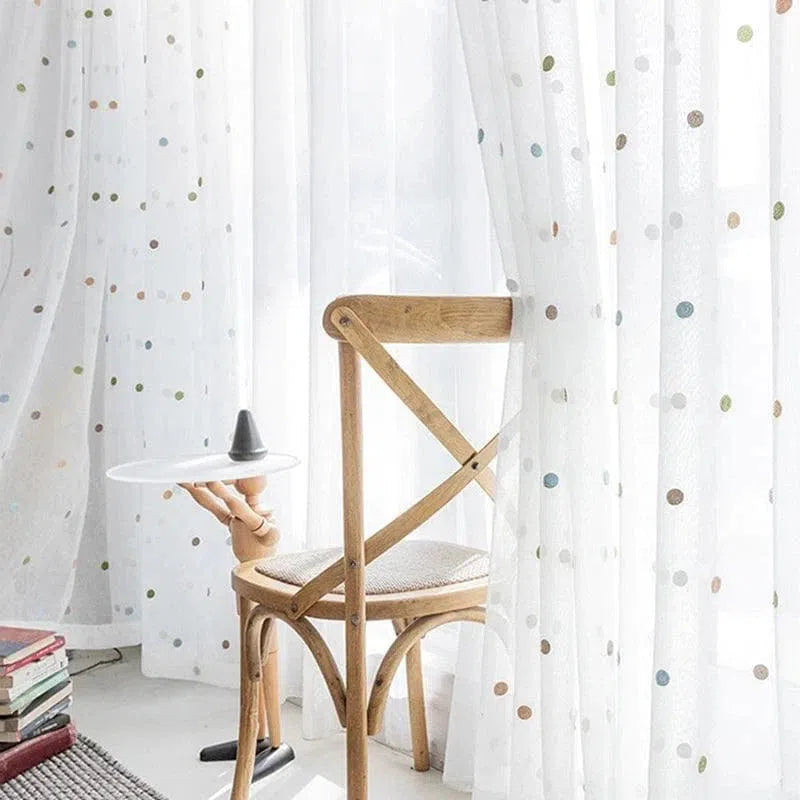 Chaise en bois design devant rideaux à motifs de pois colorés, parfaits pour ajouter une touche élégante et moderne à votre décoration intérieure. Ambiance lumineuse et accueillante pour votre salon ou espace de lecture.