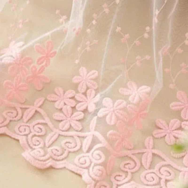 Détail délicat d'un tissu décoré de motifs floraux roses. Les fleurs brodées ajoutent une touche élégante et romantique, idéale pour les décorations d'intérieur ou la confection de vêtements raffinés. Parfait pour créer une ambiance douce et féminine dans une chambre ou un salon.