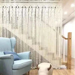 Rideau décoratif avec motifs élégants pour séparation de pièce. Ambiance cosy avec fauteuil bleu et pouf original. Idéal pour embellir un intérieur moderne. Parfait pour créer une atmosphère chaleureuse dans le salon ou l'entrée.