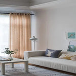 Salon moderne et lumineux avec rideaux beige, canapé confortable, coussins décoratifs à motifs animaliers et lampe élégante, créant une ambiance cosy et accueillante.