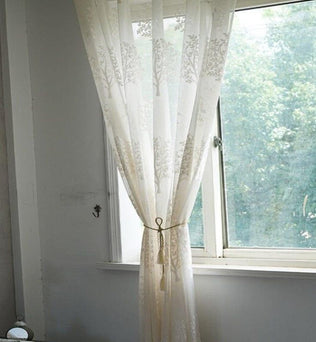 Rideau élégant avec motif floral suspendu à une fenêtre ensoleillée. Décoration intérieure élégante, parfait pour ajouter une touche de sophistication et de luminosité à votre salon ou chambre.  Accessoire idéal pour créer une ambiance chaleureuse et accueillante dans votre espace de vie.