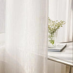 Voilage blanc élégant avec effet lumineux dans un intérieur moderne. Décoration raffinée pour salon ou chambre, apportant une ambiance douce et apaisante. Parfait pour filtrer la lumière tout en préservant l'intimité.