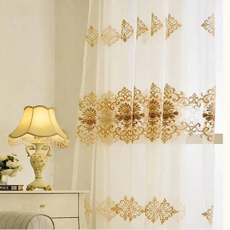 Voilage élégant brodé avec motifs floraux dorés, parfait pour apporter une touche de sophistication à votre intérieur. Idéal pour le salon ou la chambre, il s'intègre harmonieusement dans une décoration classique ou moderne. Ce rideau raffiné filtre la lumière tout en préservant votre intimité.