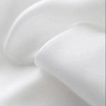 Texture de tissu blanc en gros plan, montrant des plis doux et élégants, idéal pour la literie ou la confection de vêtements confortables.