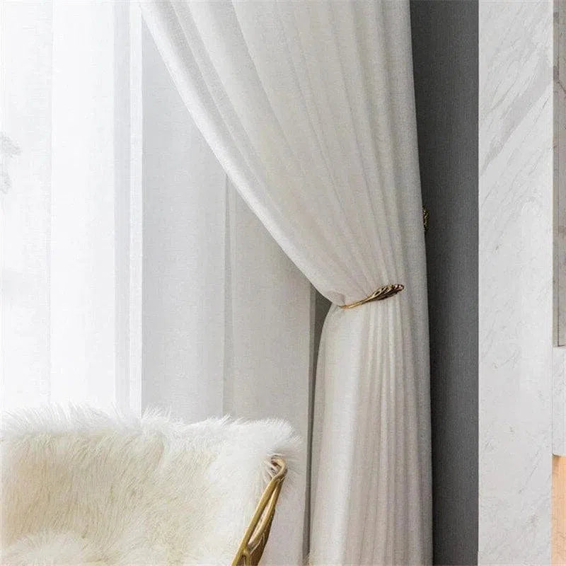 Rideaux élégants d'intérieur en blanc, offrant une ambiance lumineuse et chaleureuse à votre espace de vie. Parfait pour ajouter une touche sophistiquée à votre salon ou chambre, avec une accroche de style moderne en métal doré. Idéal pour une décoration épurée et contemporaine.