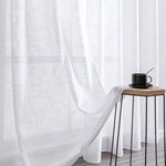 Voilage blanc élégant pour salon moderne, laissant passer la lumière tout en préservant l'intimité. Idéal pour une décoration intérieure apaisante, il s'accompagne parfaitement d'une table d'appoint au design minimaliste et d'une tasse de café pour un moment de détente. Parfait pour créer une ambiance lumineuse et sereine dans votre espace de vie.