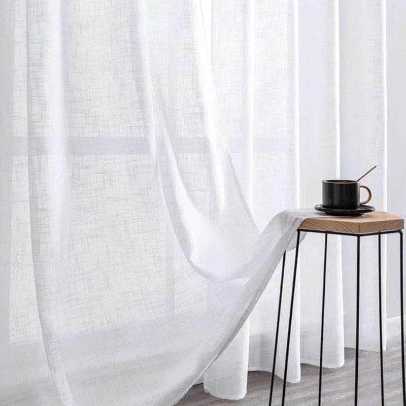 Voilage blanc élégant pour salon moderne, laissant passer la lumière tout en préservant l'intimité. Idéal pour une décoration intérieure apaisante, il s'accompagne parfaitement d'une table d'appoint au design minimaliste et d'une tasse de café pour un moment de détente. Parfait pour créer une ambiance lumineuse et sereine dans votre espace de vie.