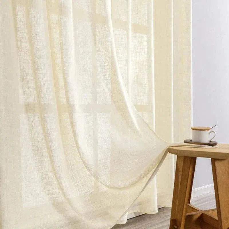 Rideau blanc élégant devant une fenêtre, apportant une ambiance paisible et lumineuse à la pièce, parfait pour l'ajout de style et de fonctionnalité à votre intérieur. Une table en bois à côté complète le décor accueillant, avec une tasse de café posée dessus. Idéal pour créer une atmosphère chaleureuse dans le salon ou la chambre.