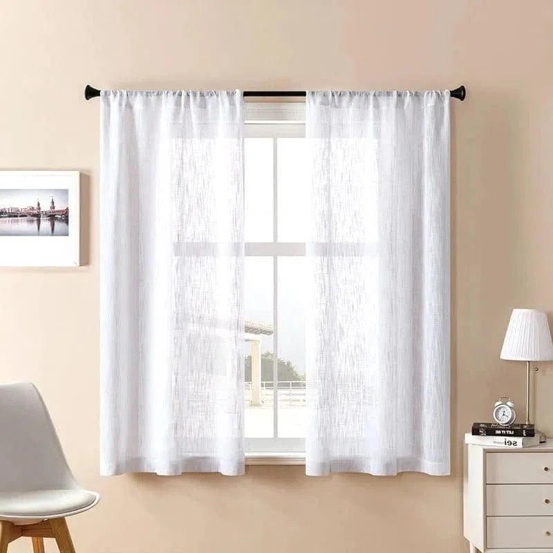 Voilage blanc élégant pour salon, installée sur une tringle noire. Décoration intérieure moderne avec chaise design, lampe de chevet et tableau encadré sur mur beige. Idéal pour filtrer la lumière naturelle tout en préservant l'intimité de votre espace de vie.