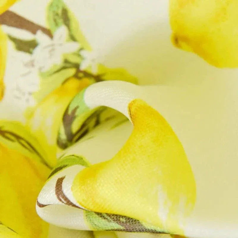 Image montrant un tissu imprimé avec des motifs de citrons jaunes vifs et des détails floraux, idéal pour des projets créatifs et décoratifs.